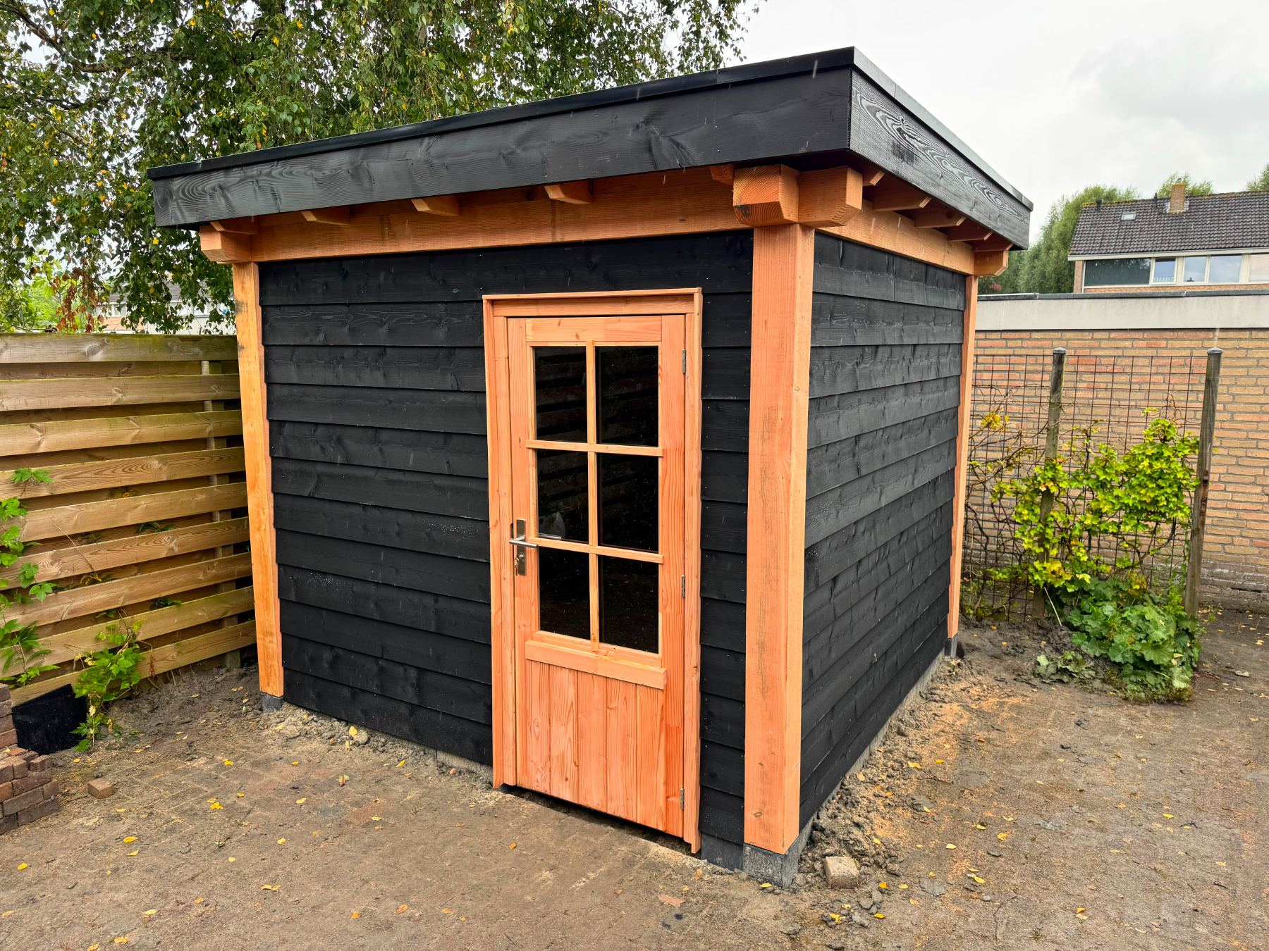 Compacte berging met zwarte bekleding en een douglas deur