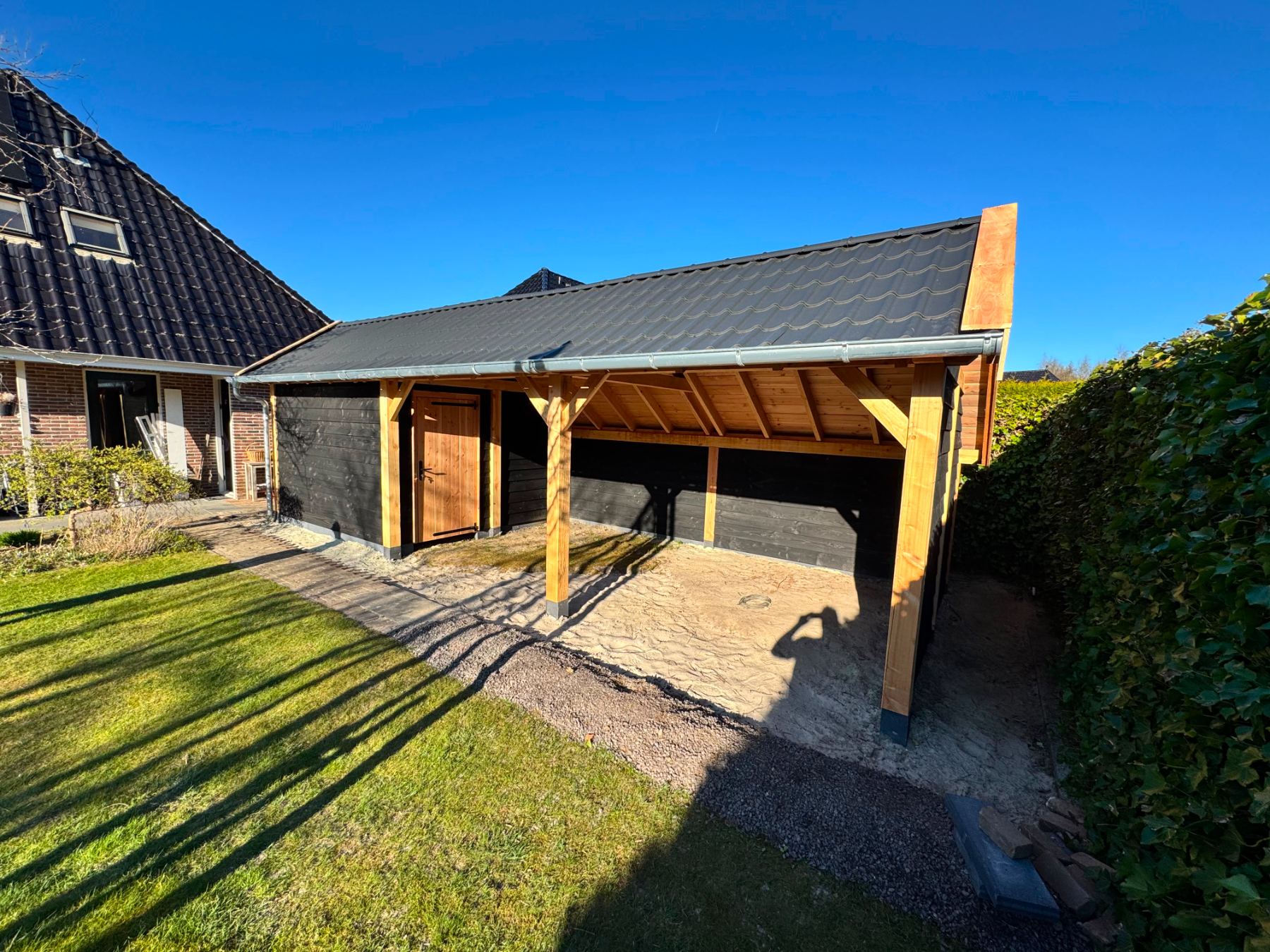 Aangebouwde overkapping met pannendak naast de woning